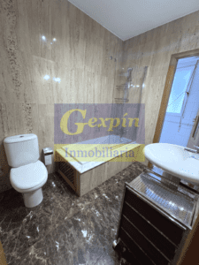 Baño acabado en mármol con bañera y mampara de cristal